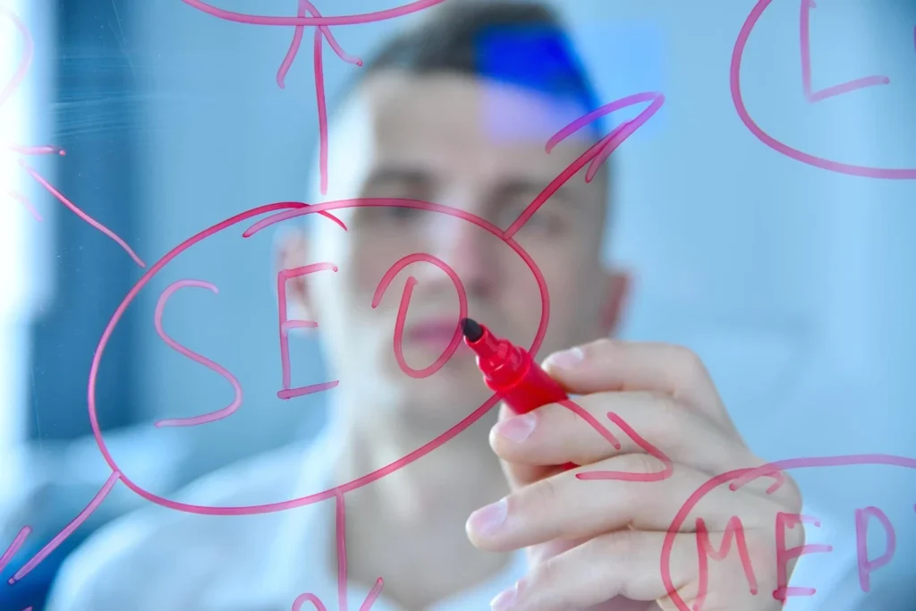 Homem escrevendo em uma superfície de vidro com uma caneta vermelha, focando em SEO e estratégias para Mapear Interessados.