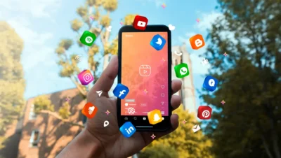 Imagem mostrando um smartphone com ícones de redes sociais flutuando ao redor. Ideal para ilustrar como montar uma estratégia de social media alinhada com os objetivos da marca.